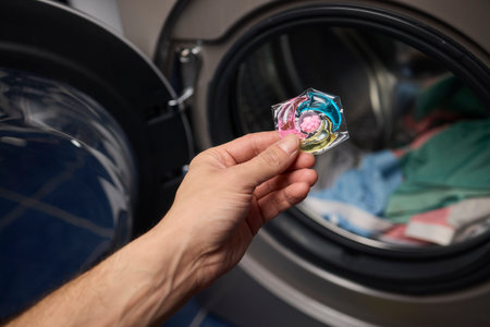 Using Laundry Detergent Pods While Doing Laundry in the Washing Machine with Clothesの写真素材