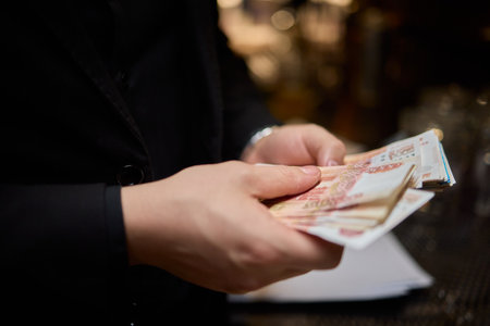 Hands are firmly holding some cash in a dark and mysterious setting that surrounds themの写真素材