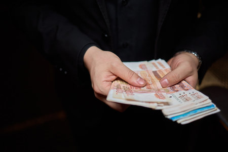Hands are firmly holding some cash in a dark and mysterious setting that surrounds themの写真素材