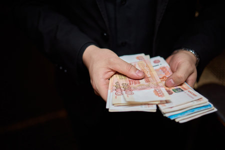 Hands are firmly holding some cash in a dark and mysterious setting that surrounds themの写真素材