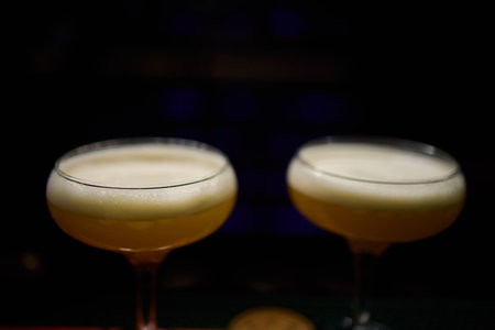 Elegant and Stunning Cocktail Glasses Clinking Together in a Softly Dimly Lit Bar Setting