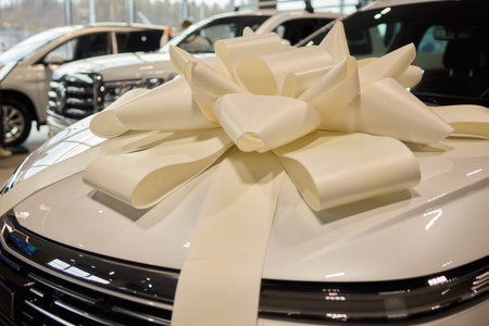 An iconic new car is being presented with a ribbon bow at the showroom for a celebratory eventの写真素材