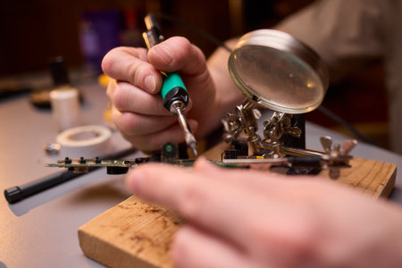 Hands Carefully Repairing a Circuit Board with a Soldering Tool for Electronics Projectsの写真素材