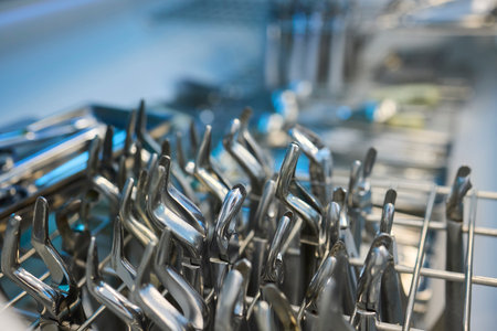 Shiny and polished cutlery resting in a tidy dishwasher basket ready for cleaningの写真素材
