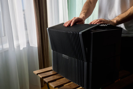 A person diligently assembling a contemporary black cooling device with precision and focus