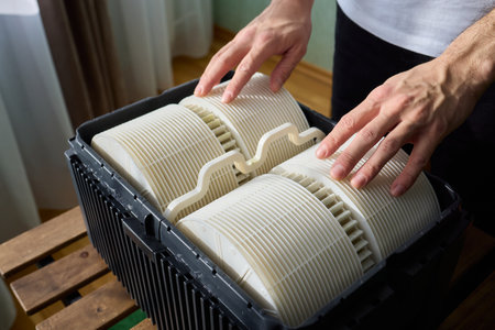 Hands are carefully handling industrial filters while inside a well-organized storage box