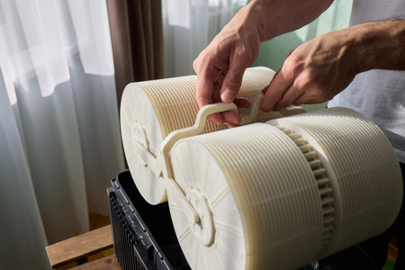Hands are carefully handling industrial filters while inside a well-organized storage boxの写真素材