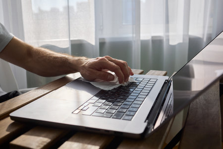 Meticulously Hand Cleaning Your Laptop with a Tissue to Achieve a Fresh and Neat Workspace