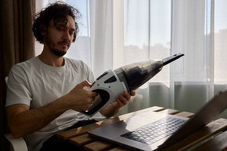 Using a handheld vacuum cleaner is an effective method for diligently cleaning a laptopの写真素材