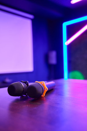 There are several colorful microphones beautifully arranged on a table in a trendy karaoke roomの写真素材