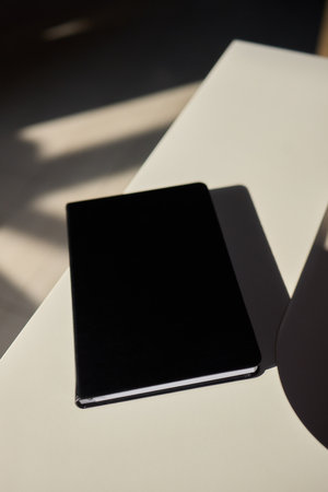 A Minimalist Black Notebook Laying on an Elegant Table Surface, Ideal for Creative Study Sessionsの写真素材