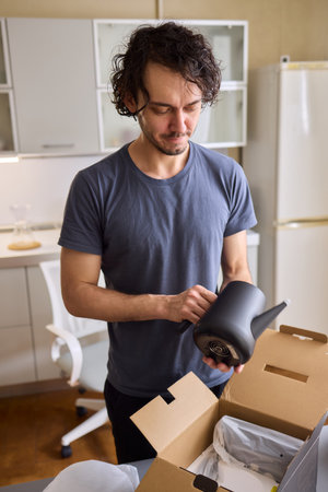 Unboxing a stylish, modern black kettle designed for use in a bright, contemporary kitchen spaceの写真素材