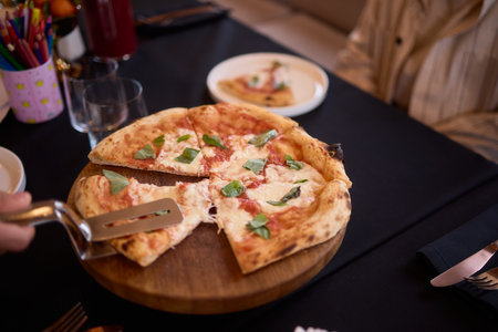 Enjoy a Delicious Fresh Margherita Pizza beautifully presented on a Rustic Wooden Boardの写真素材