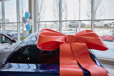 The new car is wrapped in a red bow. Beautiful gift concept.の写真素材