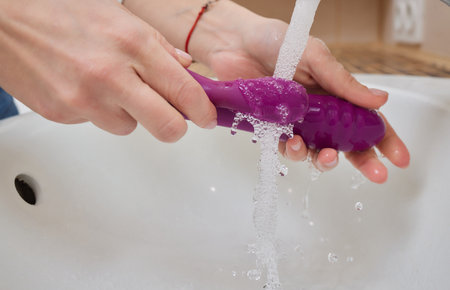young woman washes a toy in the sink at home.の写真素材