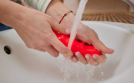young woman washes a toy in the sink at home.の写真素材