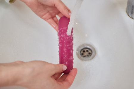 young woman washes a toy in the sink at home.の写真素材