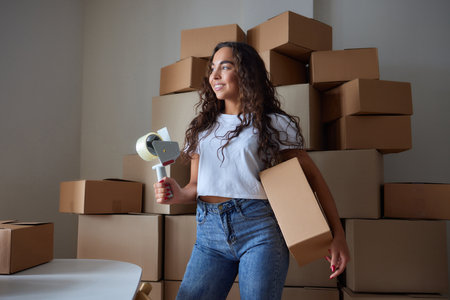 Happy woman unpacking container at home, opening carton box, looking inside package. Smiling...