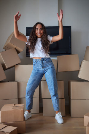 Young beautiful hispanic woman smiling confident packing cardboard box at new home.の写真素材