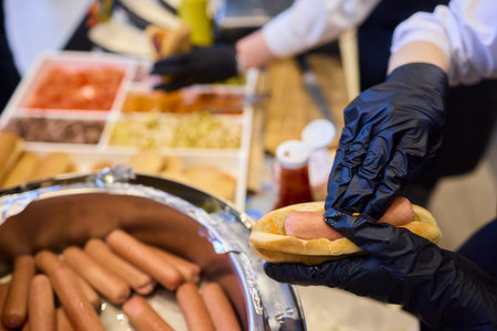 Staff Members Preparing a Delicious Hot Dog with Ketchup at the Event Taking Placeの写真素材