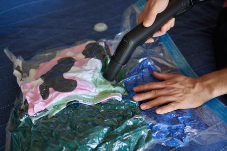 The girl pumps out air with a vacuum cleaner from a vacuum bag with clothes. The concept of storage...