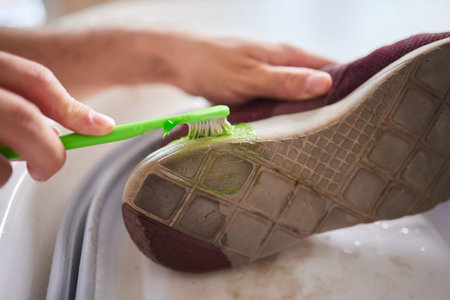 Hand cleans red shoes with a toothbrush. life hack for the care of suede.の写真素材