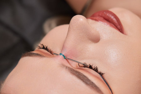 Nose Bridge Piercing Professional holding the jewel of piercing day just before screw the ball.の写真素材