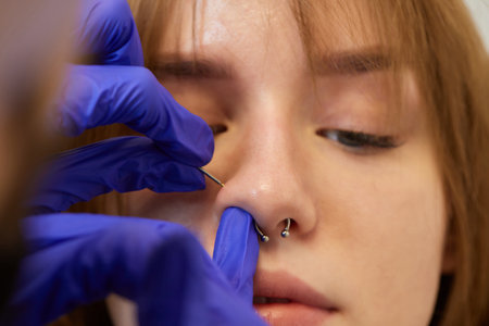 Young woman doing piercing nose ring at beauty studio salon.