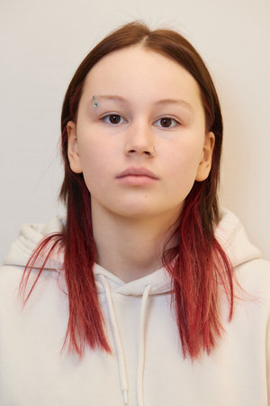 Beautiful young woman getting her eyebrow pierced, body piercer wearing blue gloves.