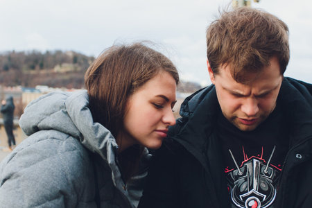 Happy couple consulting a smart phone in winter in the street.の写真素材
