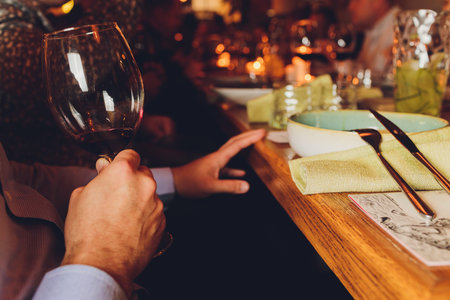 male hand holding glass of red wine.の写真素材