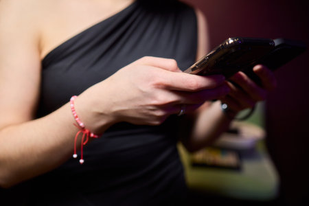 A Fashionable Individual in a Social Setting, Using Two Smartphones to Enhance Connectivity