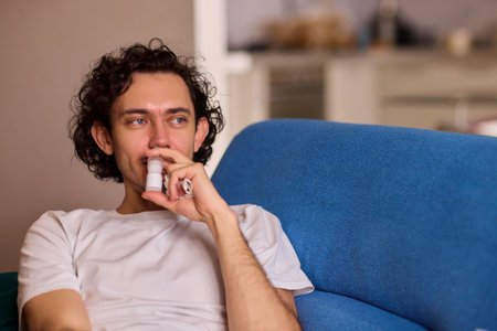 A Man Using an Inhaler While He is Relaxing Comfortably at Home in a Cozy Environmentの写真素材