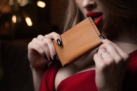 An Elegant Woman Holding a Stylish and Chic Leather Wallet While Dressed in a Lovely Red Dressの写真素材