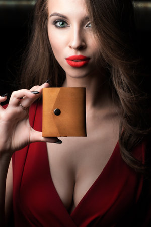 An Elegant Woman Holding a Stylish and Chic Leather Wallet While Dressed in a Lovely Red Dressの写真素材