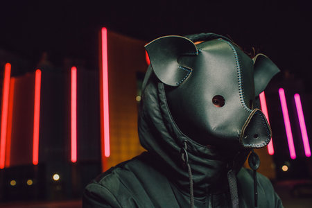 A mysterious individual wearing a pig mask stands under vibrant neon lights, captivating allの写真素材
