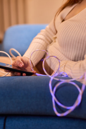 A person is engaged with their smartphone while surrounded by various charging cablesの写真素材