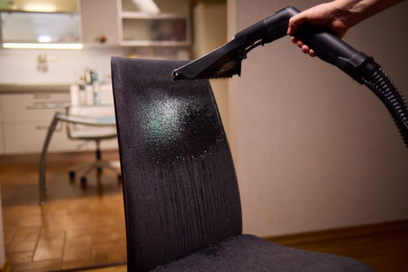 Using a Vacuum Cleaner for Upholstery Cleaning in a Modern Interior Design Settingの写真素材