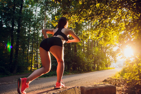 A Runner Getting Ready for a Sprint at Sunset in a Serene, Lush Forest Landscapeの写真素材