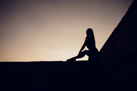 An Athletic Woman Engaging in Stretching Exercises on a Rooftop During a Beautiful Sunsetの写真素材