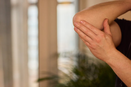 A closeup image showcasing a hand actively examining a particular skin condition on an elbow region