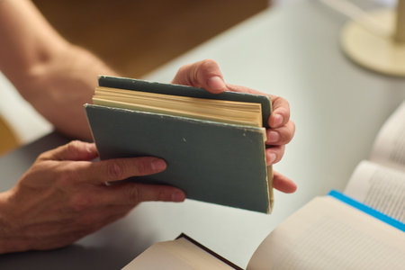 Hands purposefully engaged with an engrossing book carefully placed on a table surface
