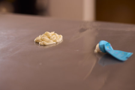 A closeup view of a sticky substance resting on a surface while being handled with a tool