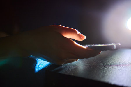 A Hand Gripping a Smartphone in a Low Light Environment, Showcasing Modern Technology and Designの写真素材