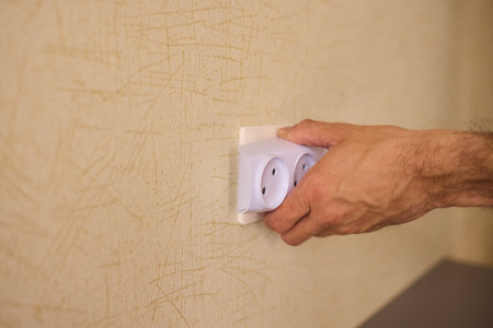 Manually plugging a device into a wall socket requires careful attention to ensure safety at home