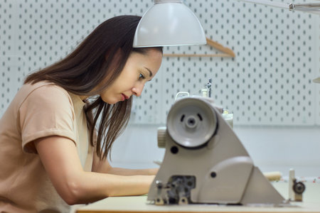 A Focused Seamstress Diligently Working with a Sewing Machine in Her Creative Workspace