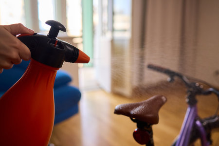 Engaging in Bicycle Cleaning with a Convenient Spray Bottle in a Cozy Environment Spaceの写真素材