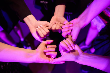 Friends forming a heart shape with hands in a colorful setting, symbolizing their bondの写真素材