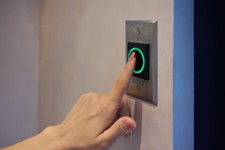 Hand Pressing a Modern Elevator Button That Features a Green Light Indicator for Operationの写真素材