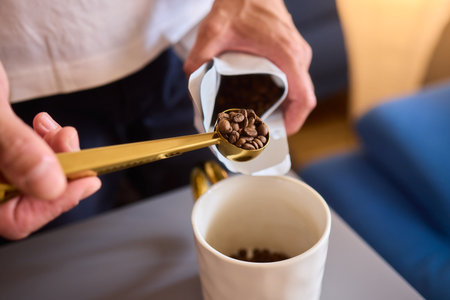 Pouring freshly ground coffee beans into a measuring cup for a perfect morning brewの写真素材